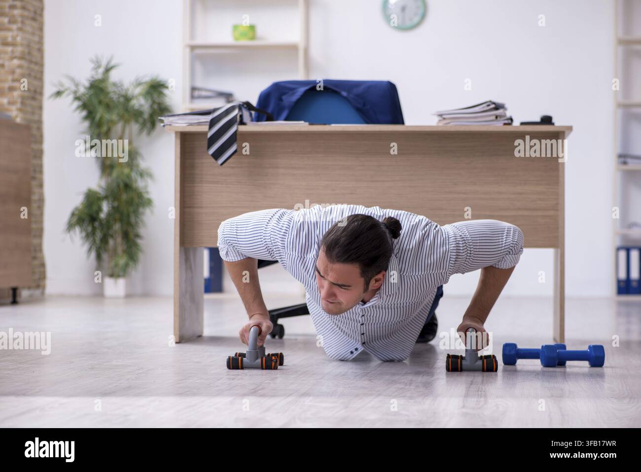 Handsome male employee doing exercises in office Stock Photo