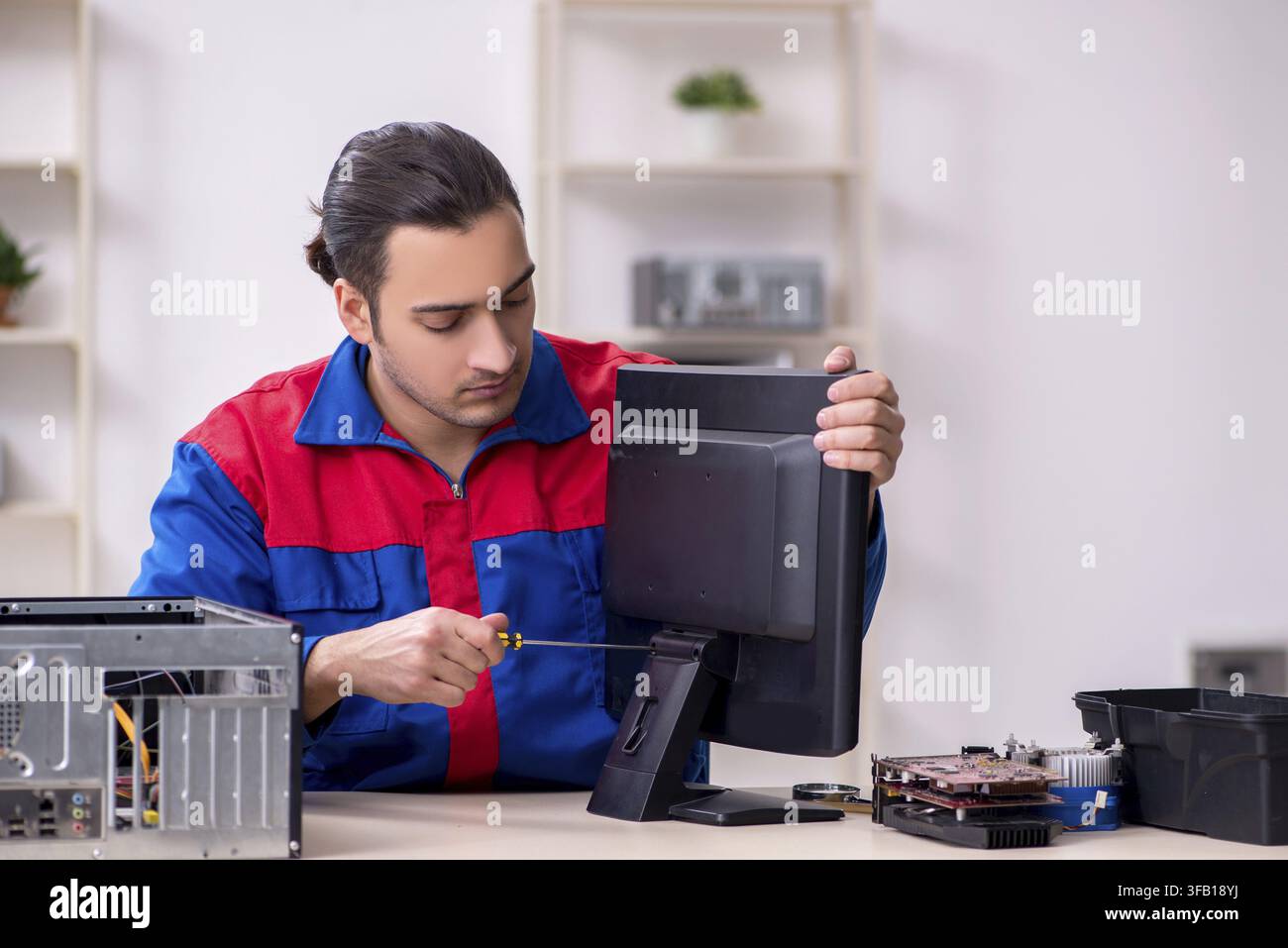 Young male mechanic repairs computer PC Stock Photo