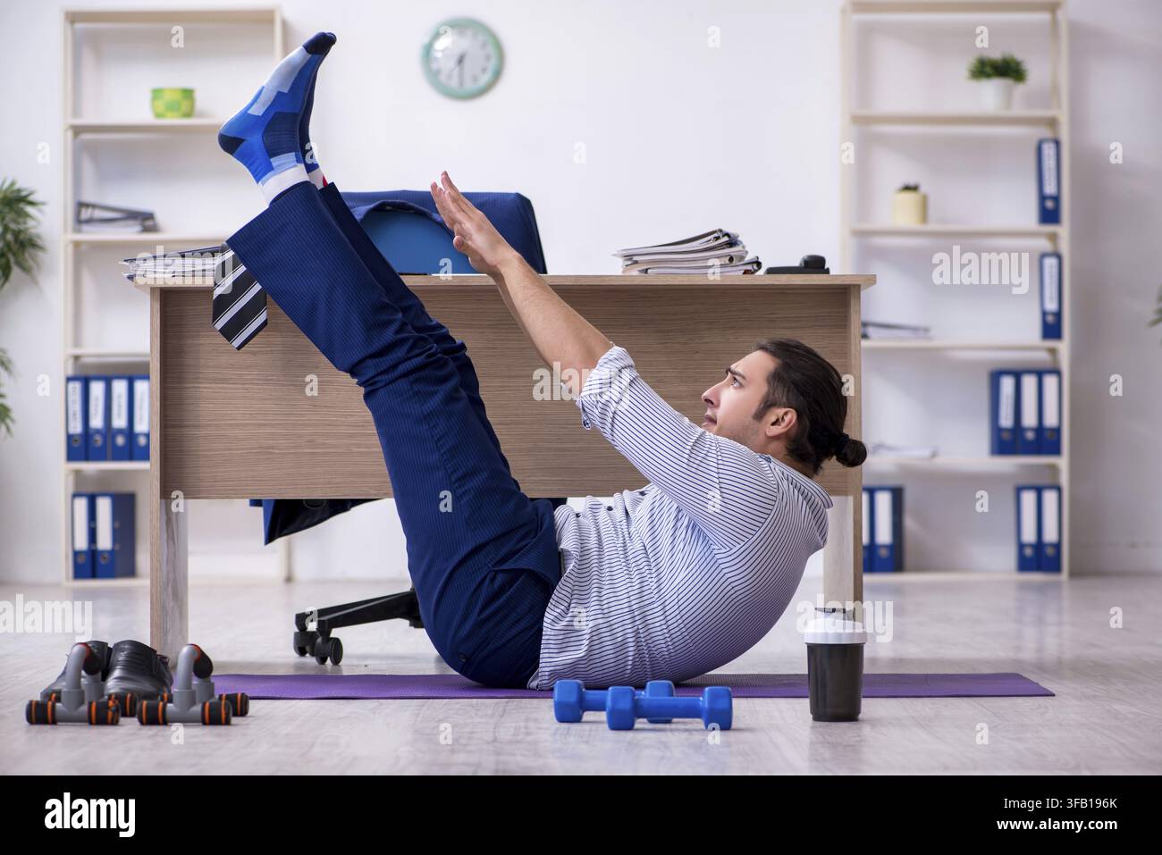 Handsome male employee doing exercises in office Stock Photo