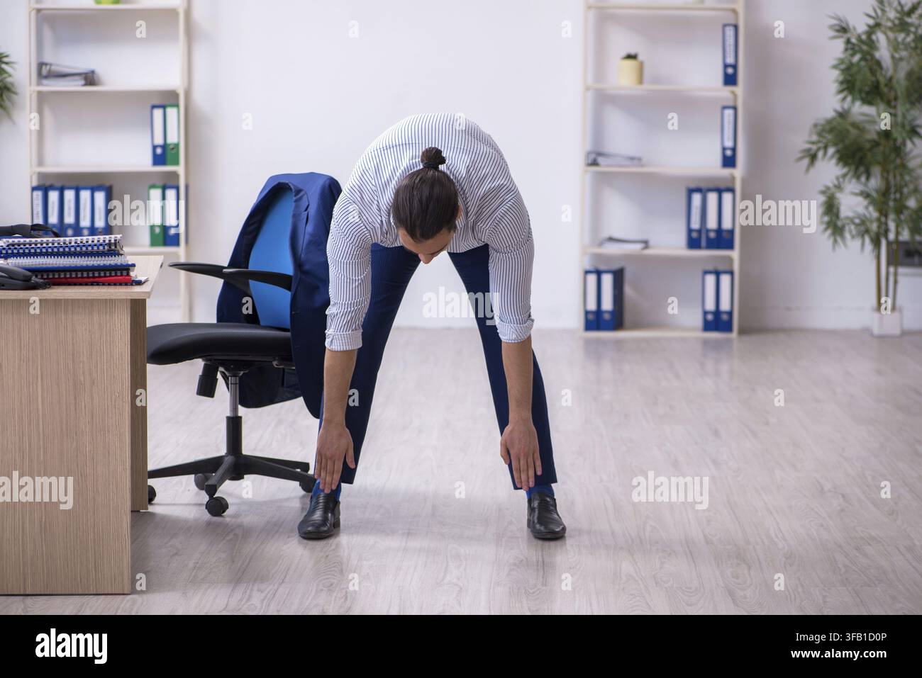 Handsome male employee doing exercises in office Stock Photo