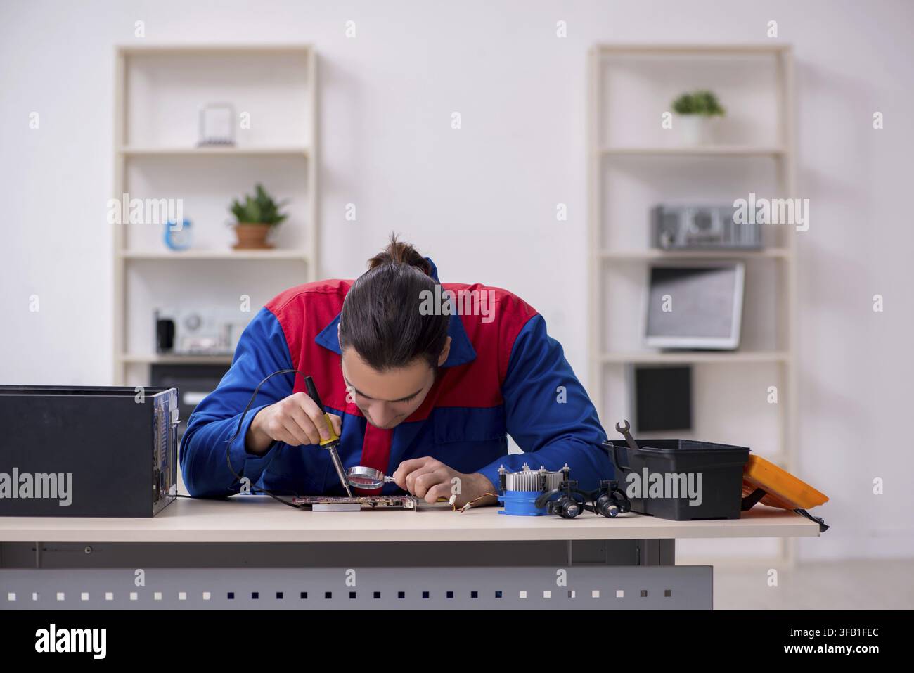 Young male mechanic repairs computer PC Stock Photo