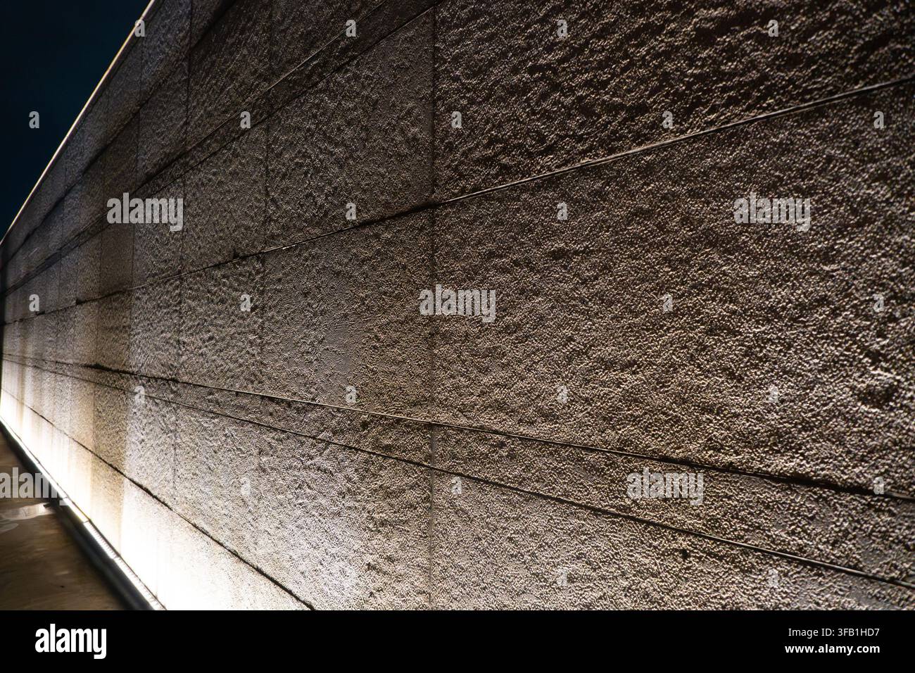 Textured concrete wall illuminated at night. Stock Photo
