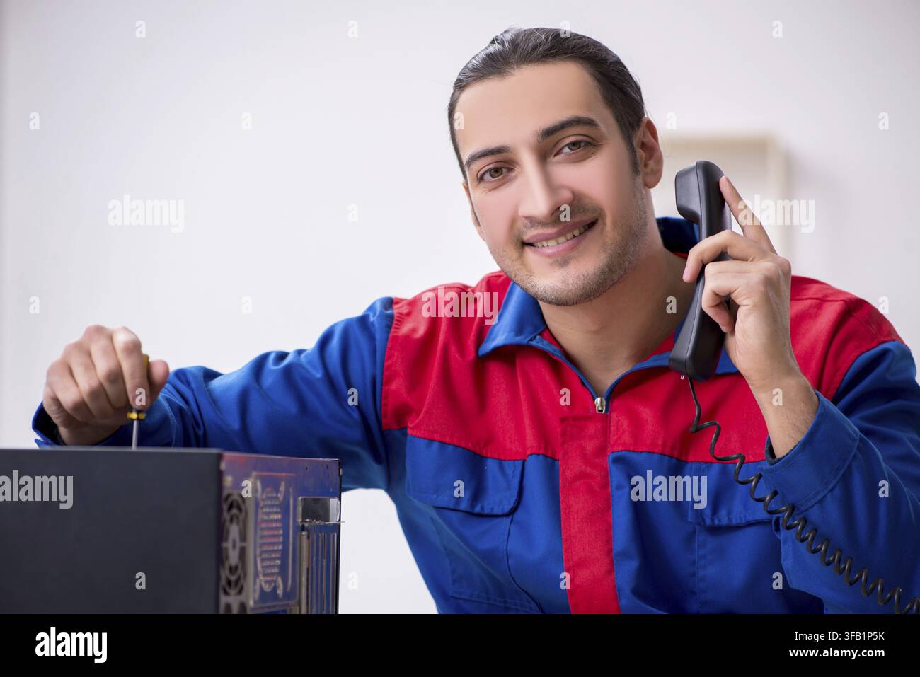 Young male mechanic repairs computer PC Stock Photo
