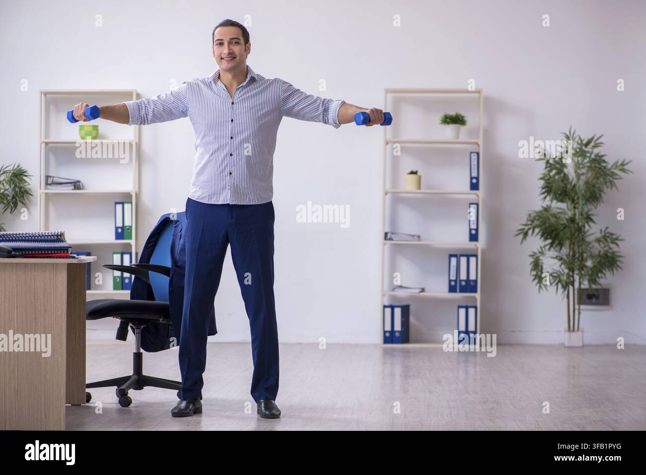 Handsome male employee doing exercises in office Stock Photo