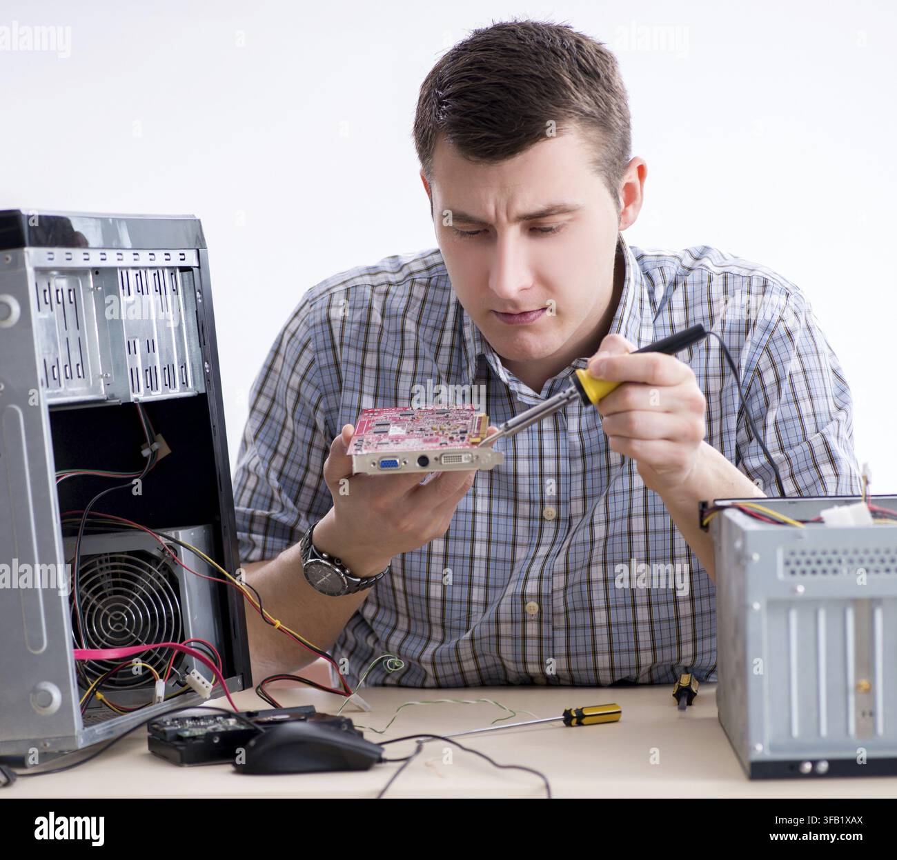 The young technician repairs computers in the workshop Stock Photo