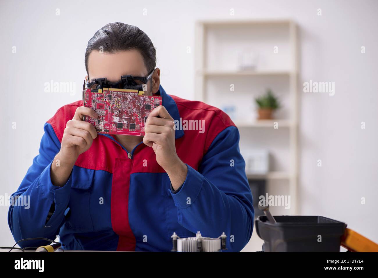 Young male mechanic repairs computer PC Stock Photo