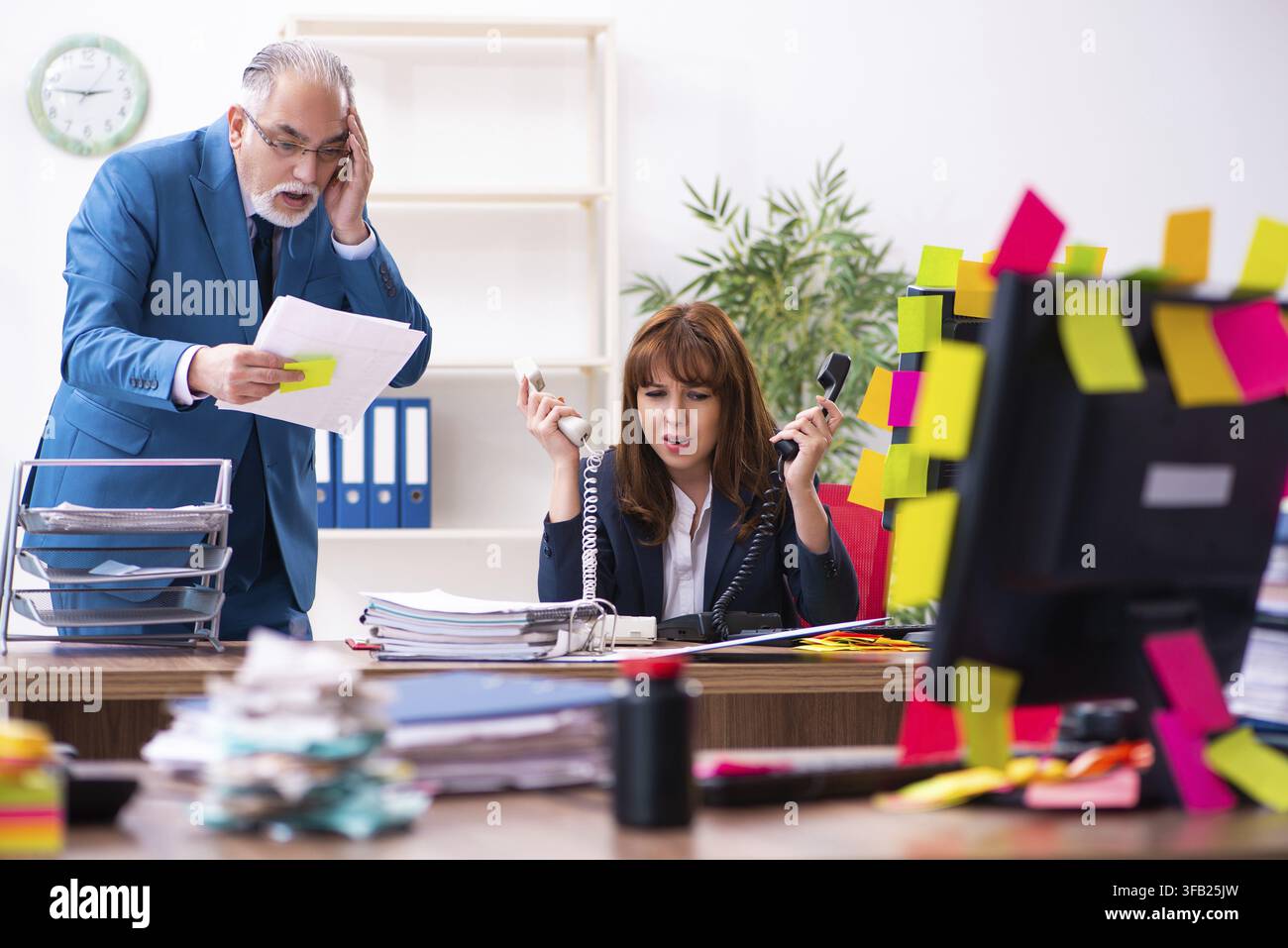 Two employees and excessive work in the office Stock Photo