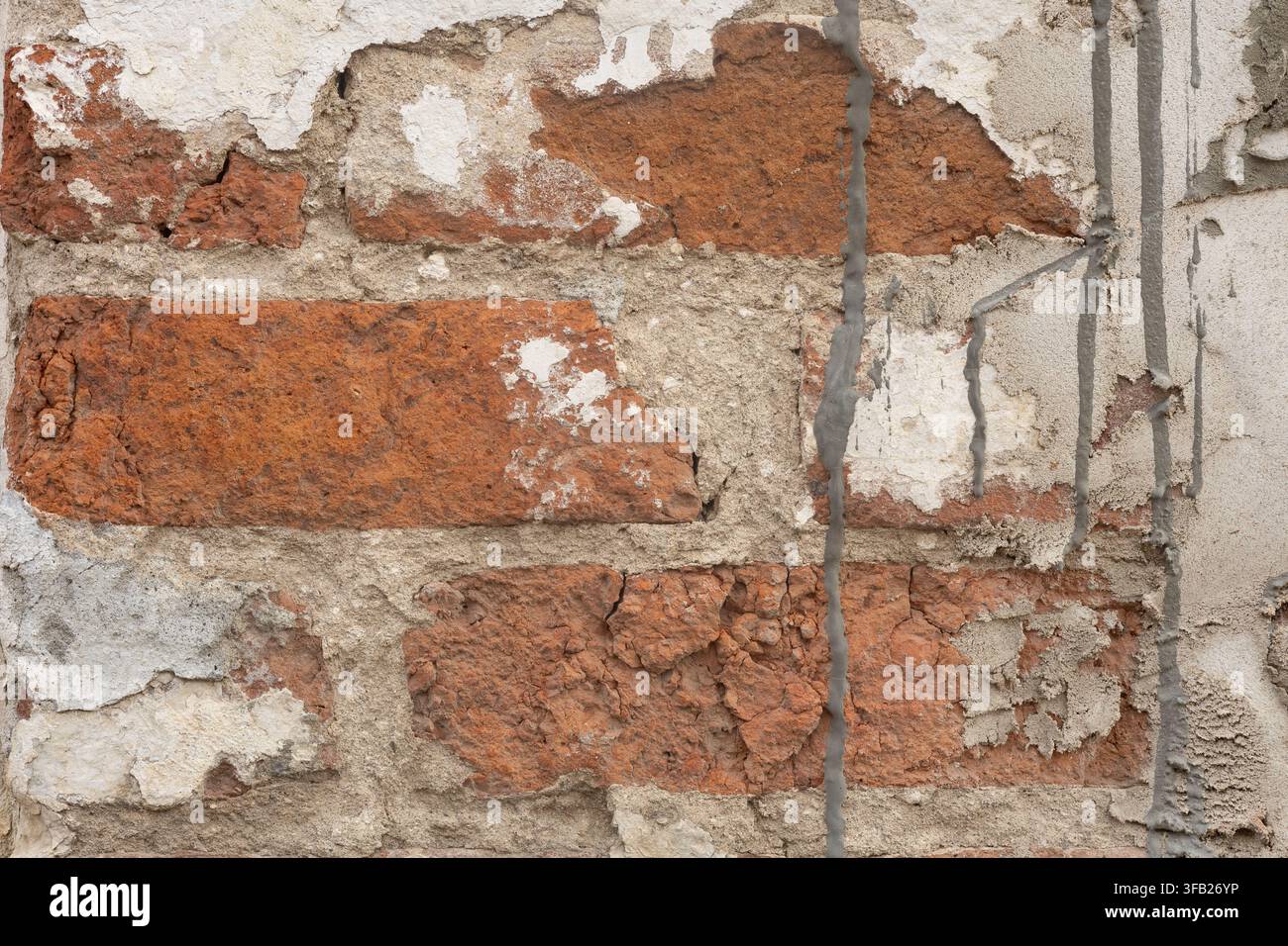 Old red brick wall texture, damaged plaster on brickwork with concrete cement drips, grunge weathered architectural background. Stock Photo