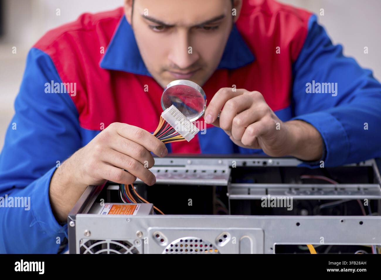 Young male mechanic repairs computer PC Stock Photo
