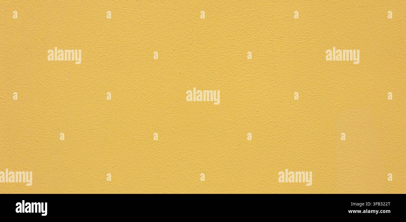 Yellow wall surface featuring a grainy painted texture for background use Stock Photo