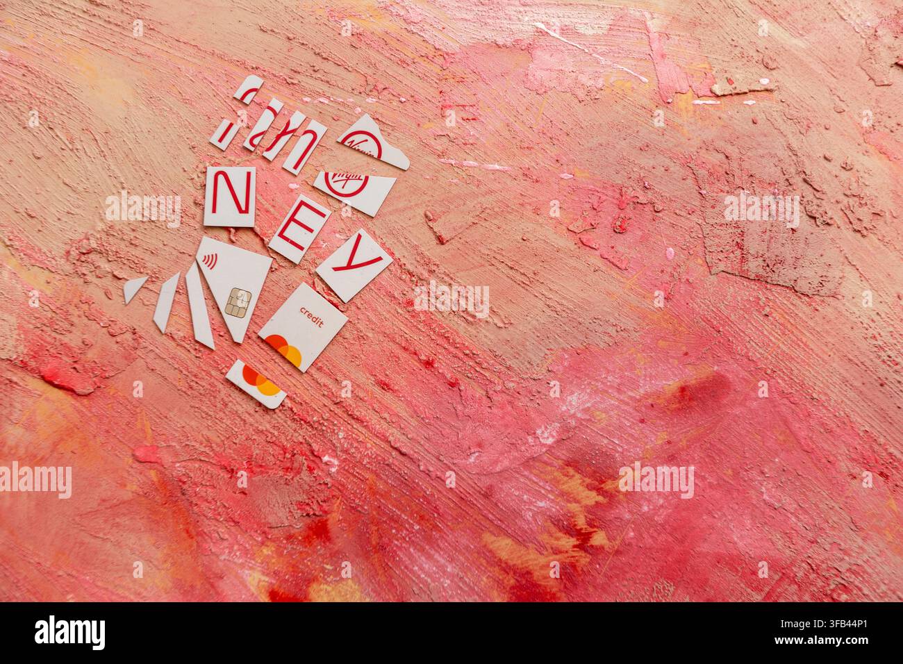 Against a textured red background a Virgin Money Mastercard credit card has been cut in to pieces perhaps too enthusiastically but tidily arranged. Stock Photo