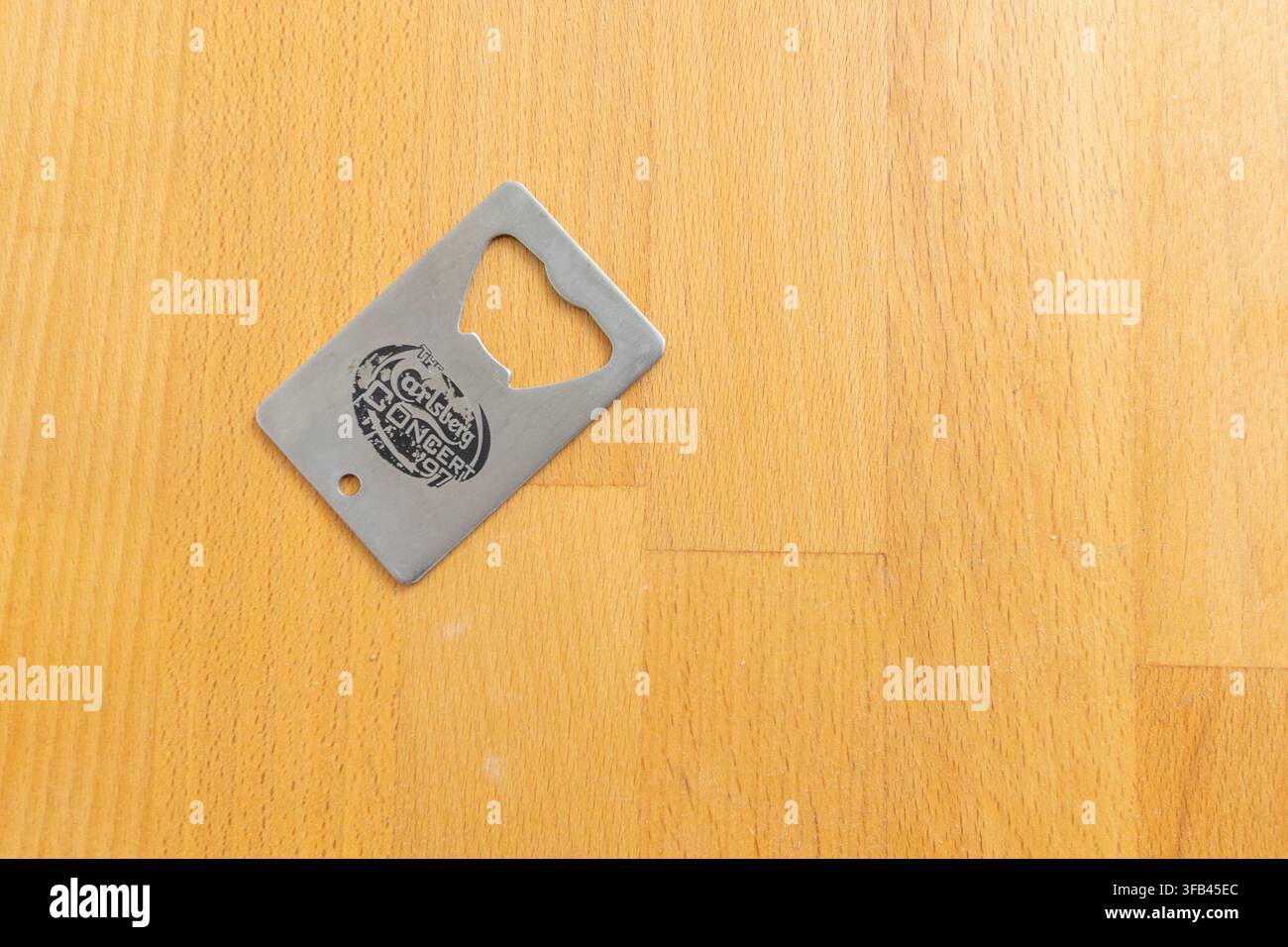 A simply designed stainless steel and well used brewery giveaway combined key fob and bottle opener/cap lifter marked "Carlsberg concert '97". Stock Photo