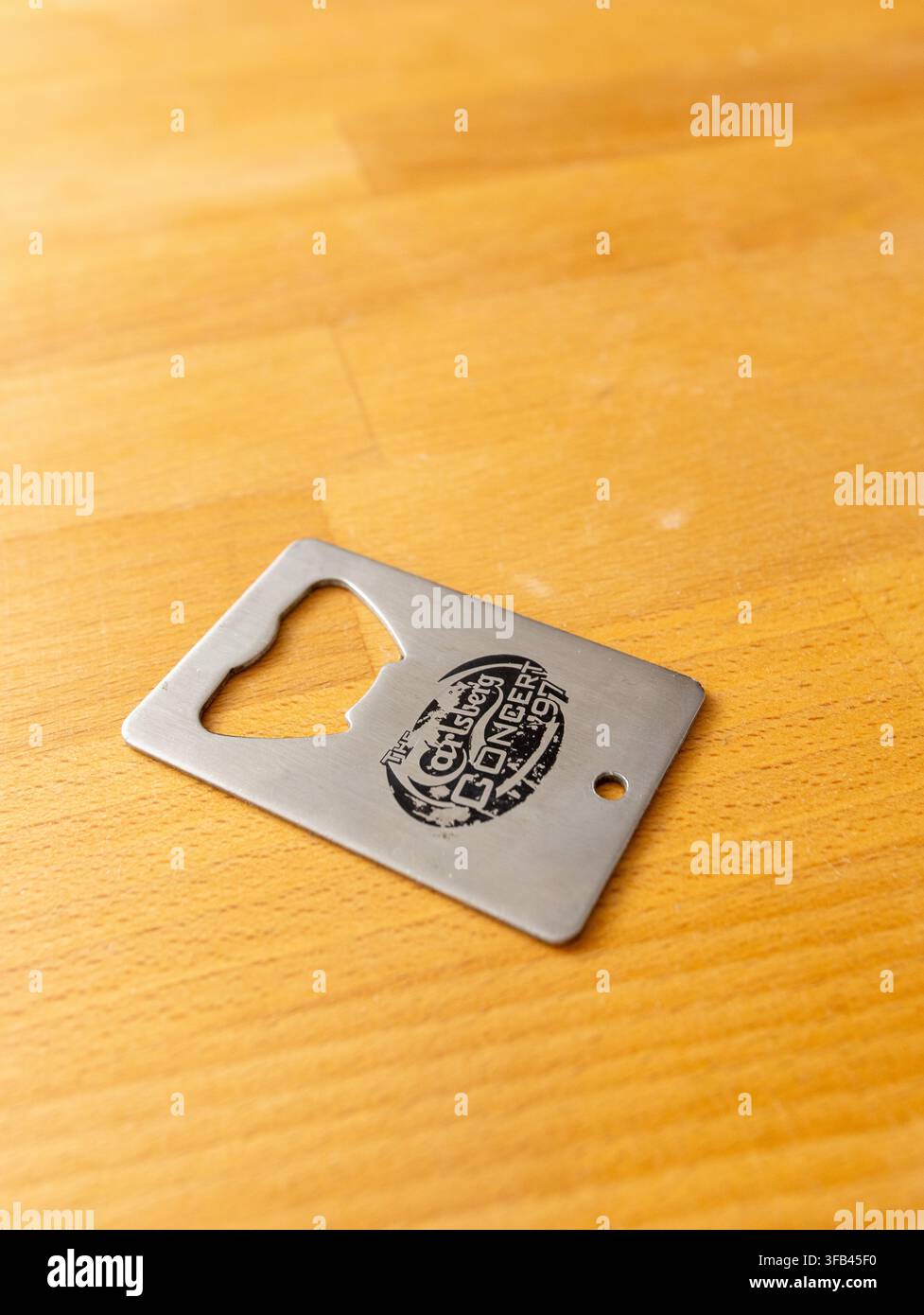 A simply designed stainless steel and well used brewery giveaway combined key fob and bottle opener/cap lifter marked "Carlsberg concert '97". Stock Photo