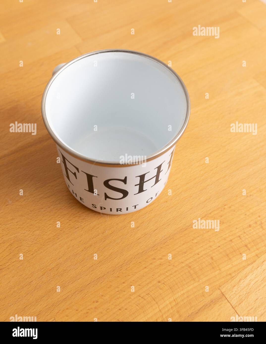 White stove enamel mug with the slogan "The Spirit of the Coast" for Aldeburgh distillers Fishers Gin who are virtually on the beach in Suffolk. Stock Photo