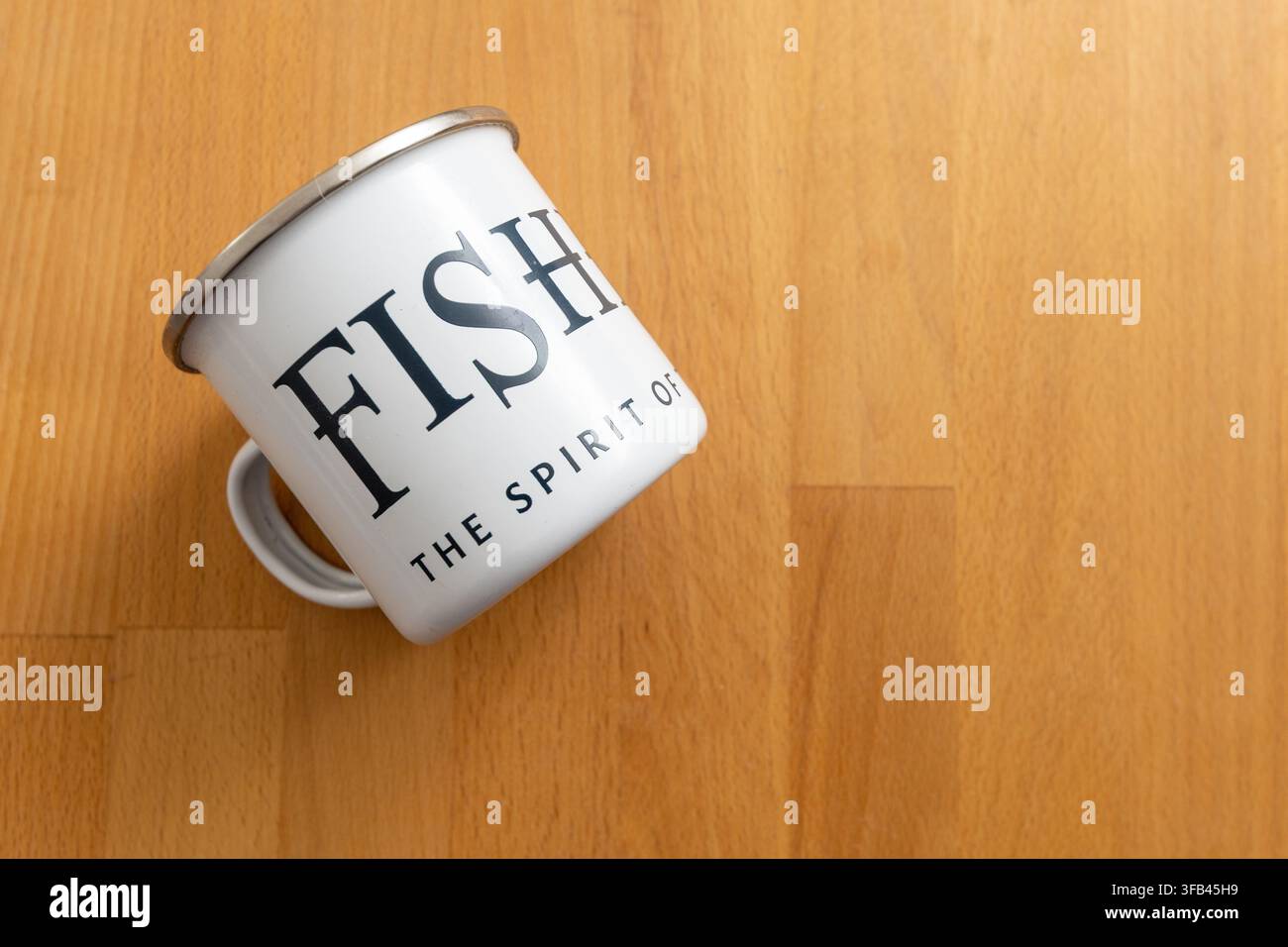 White stove enamel mug with the slogan "The Spirit of the Coast" for Aldeburgh distillers Fishers Gin who are virtually on the beach in Suffolk. Stock Photo