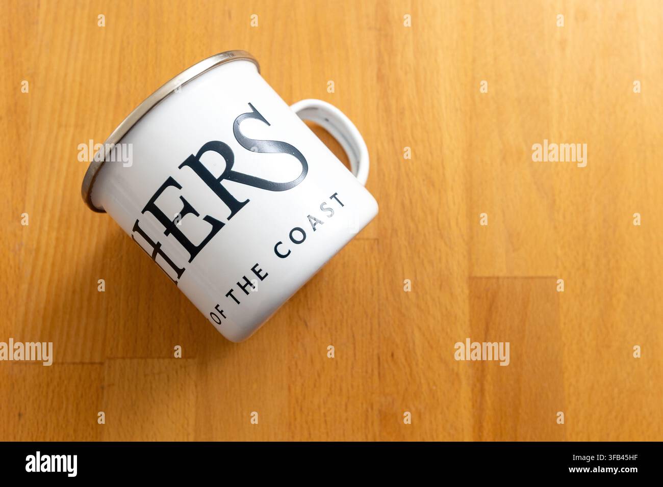 White stove enamel mug with the slogan "The Spirit of the Coast" for Aldeburgh distillers Fishers Gin who are virtually on the beach in Suffolk. Stock Photo