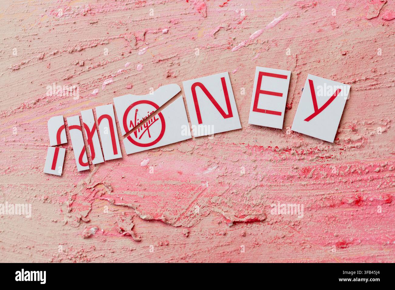 Against a textured red background a Virgin Money Mastercard credit card has been cut in to pieces perhaps too enthusiastically but tidily arranged. Stock Photo