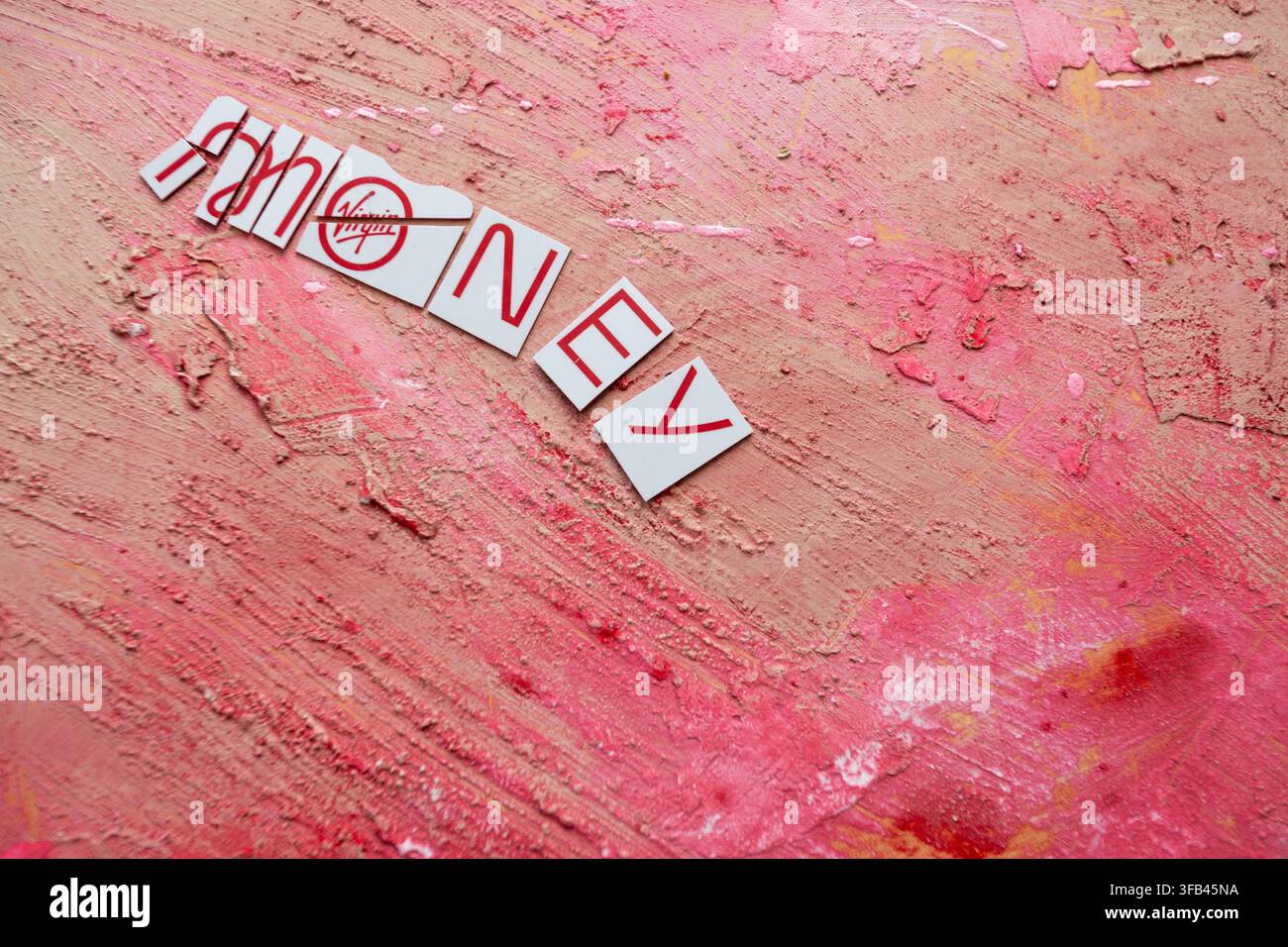 Against a textured red background a Virgin Money Mastercard credit card has been cut in to pieces perhaps too enthusiastically but tidily arranged. Stock Photo