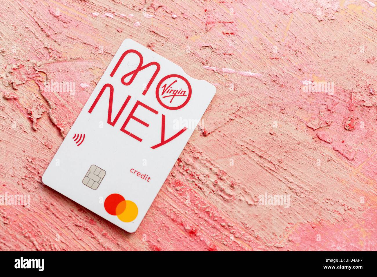 The elegantly simple design of a Virgin Money credit card with symbols and logos laying on a textured red background temptingly waiting to be used. Stock Photo