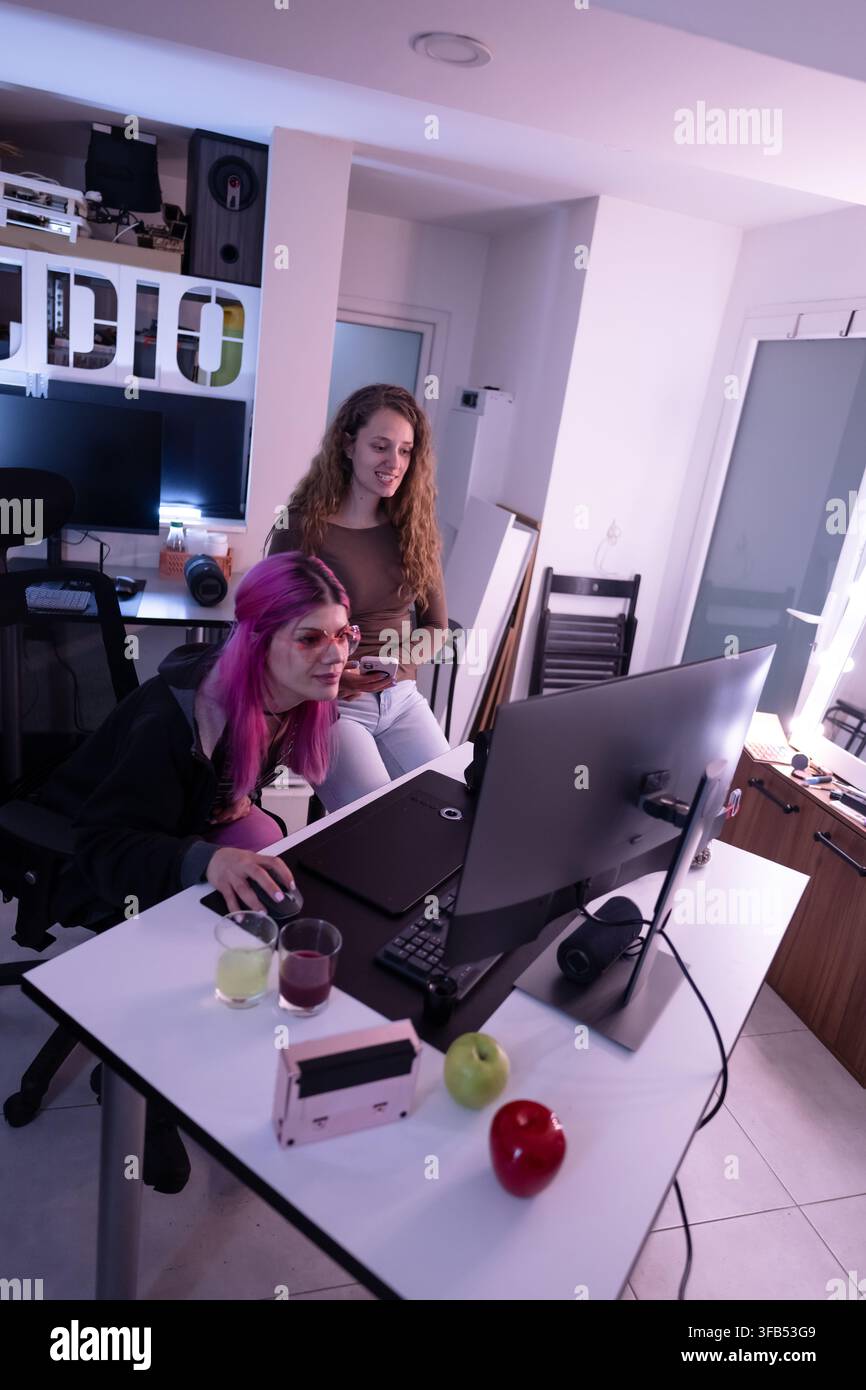 Two creative designers collaborating on a desktop computer in a modern workspace with stylish decor Stock Photo