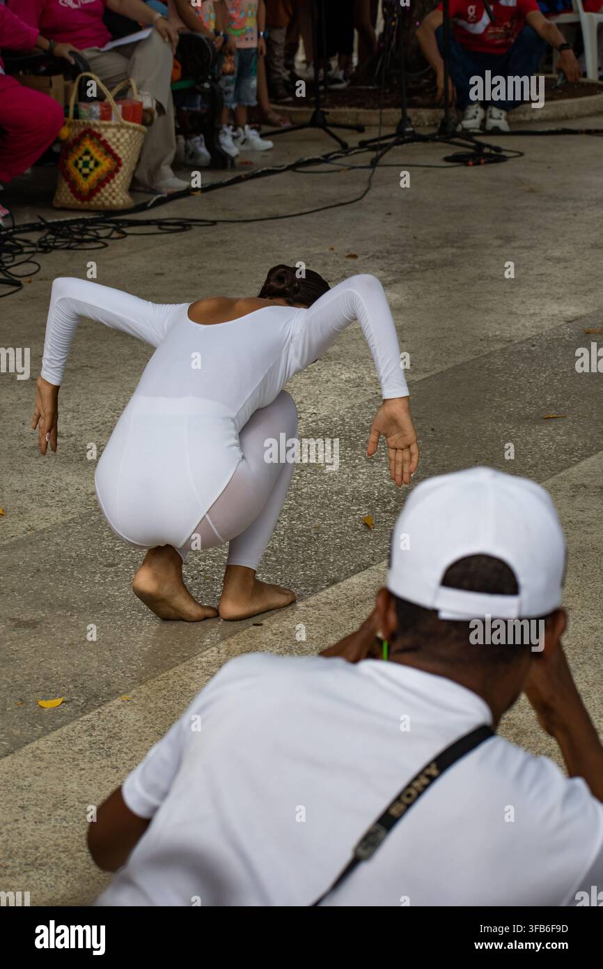 Man photographs a dancer performing in a white leotard at El Carnavalito in Ciego de Ávila, Cuba, on August 21, 2026. Stock Photo