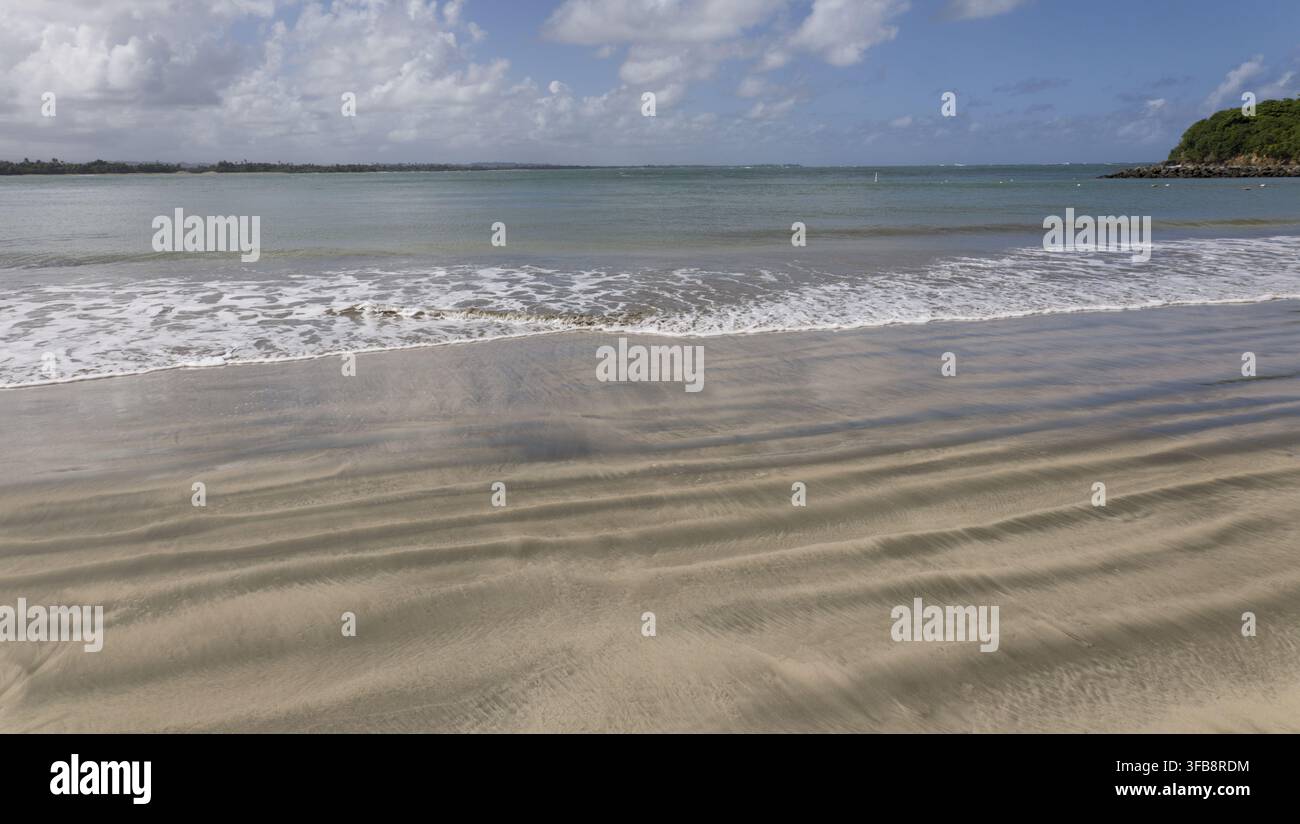 Rolling waves breaking onto a sandy tropical beach Stock Photo