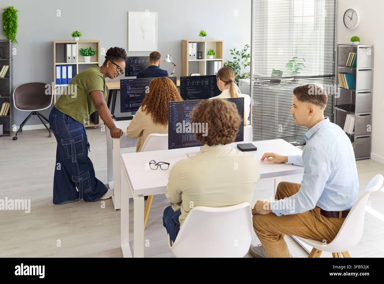 Programmers and developers collaborating on code in office during team meeting Stock Photo