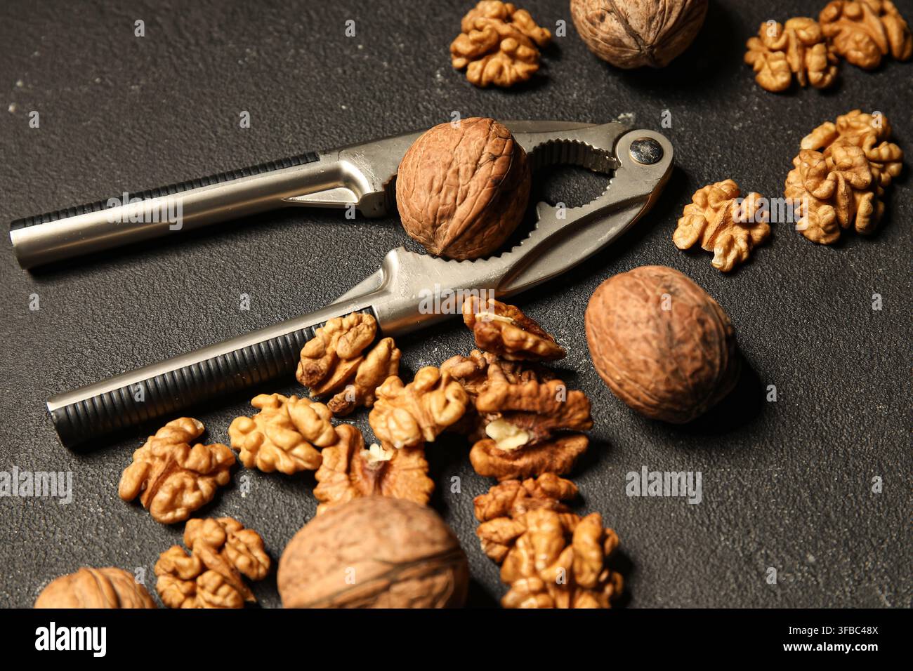 Tasty walnuts and nutcracker on black background Stock Photo