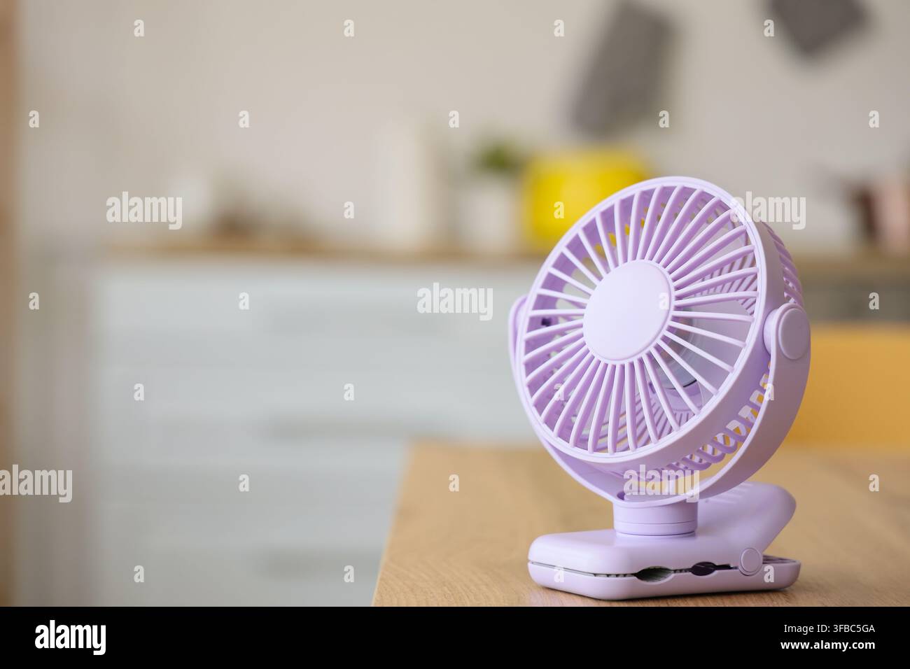 Lilac mini fan on table in kitchen, closeup Stock Photo