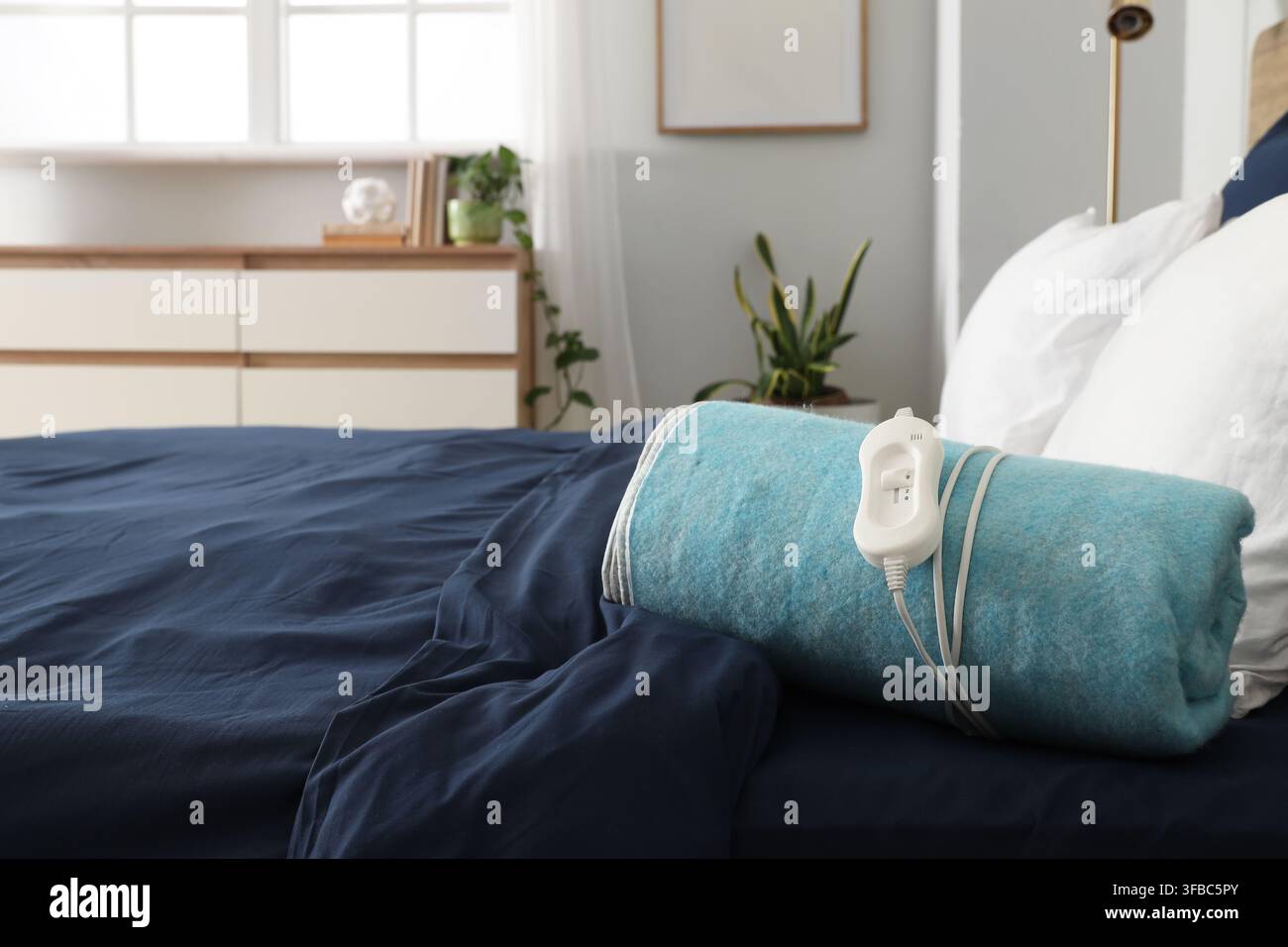 Folded electric heating pad on bed in room Stock Photo