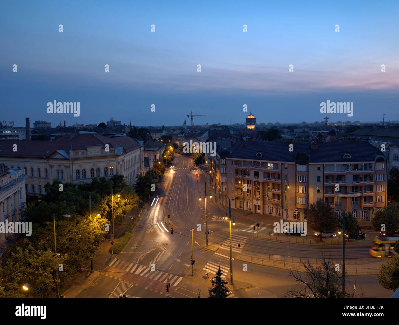 City street at dusk with light trails and tall buildings Stock Photo