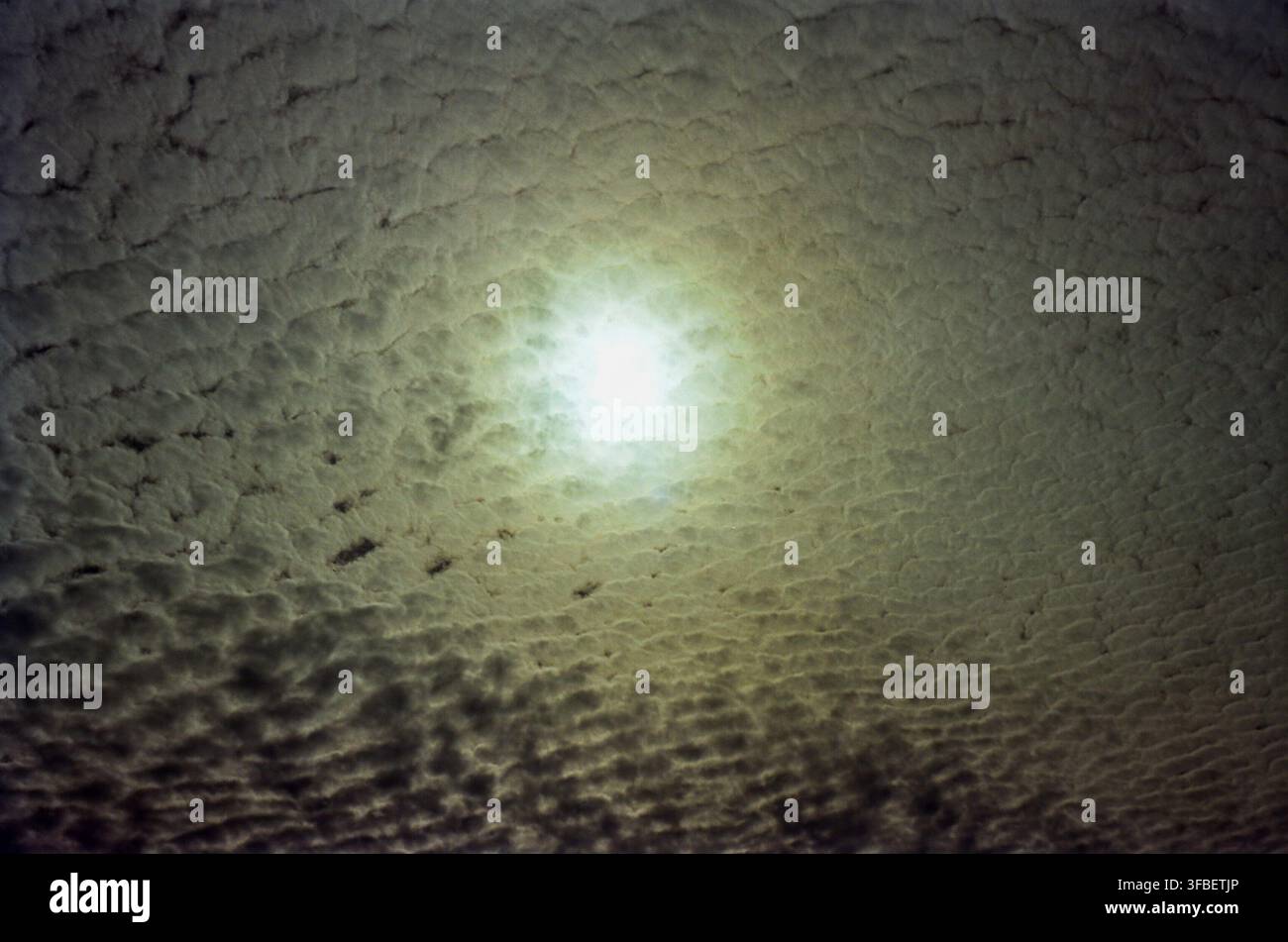 Sun Glowing Through Dense Textured Clouds Stock Photo