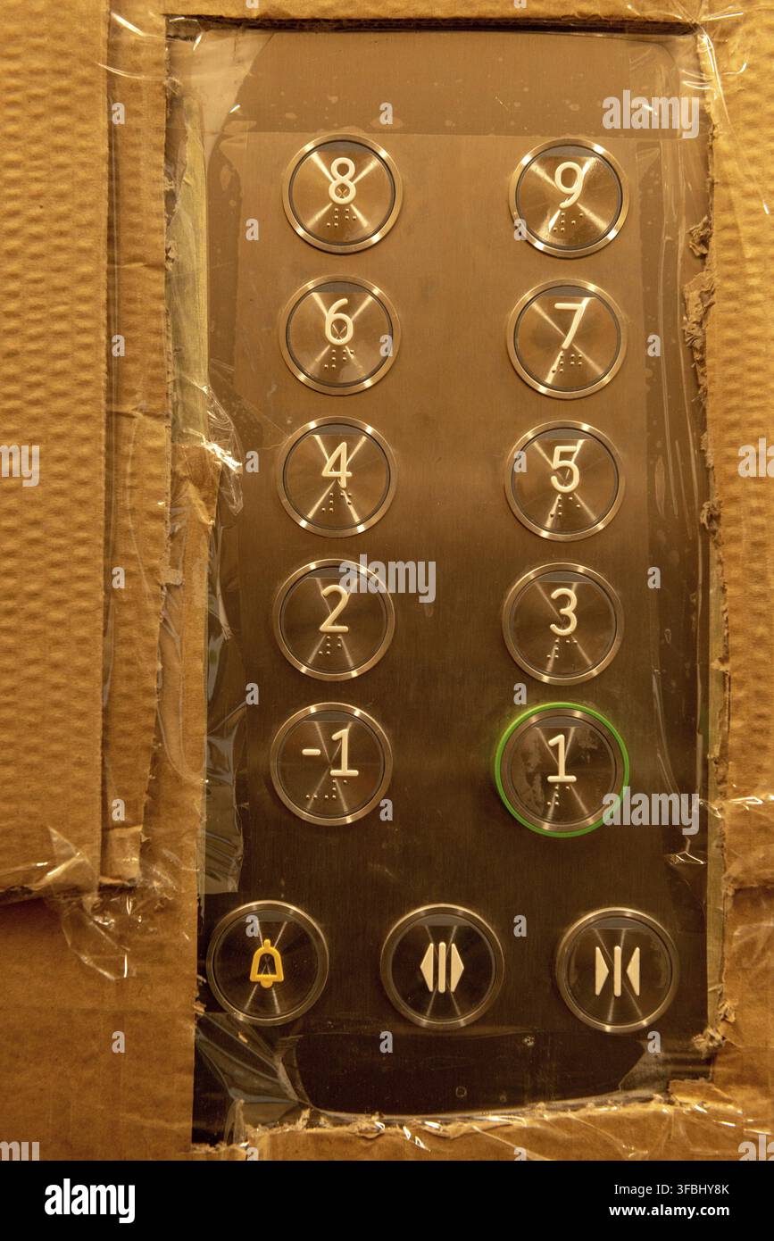 Cardboard wrapped lift elevator control panel and buttons with missing 0 level. Protected lift elevator during construction works Stock Photo