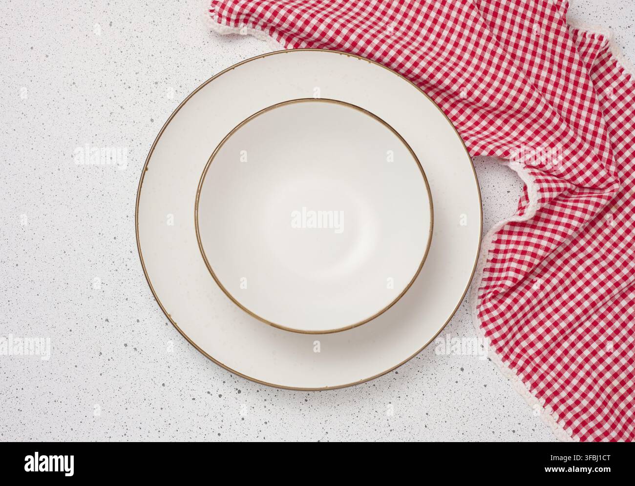 Round white ceramic empty plates and red kitchen towel, top view Stock Photo