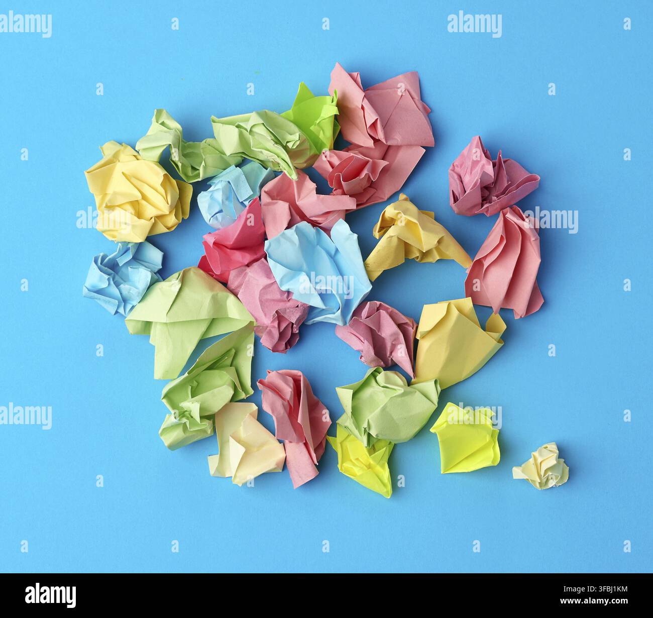 Crumpled multi-colored paper stickers, top view, blue background, close up Stock Photo