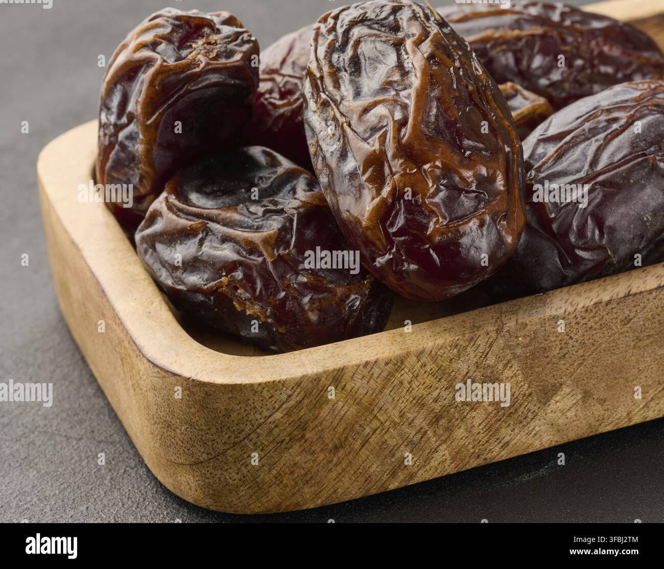 Ripe large dates in a wooden plate Stock Photo