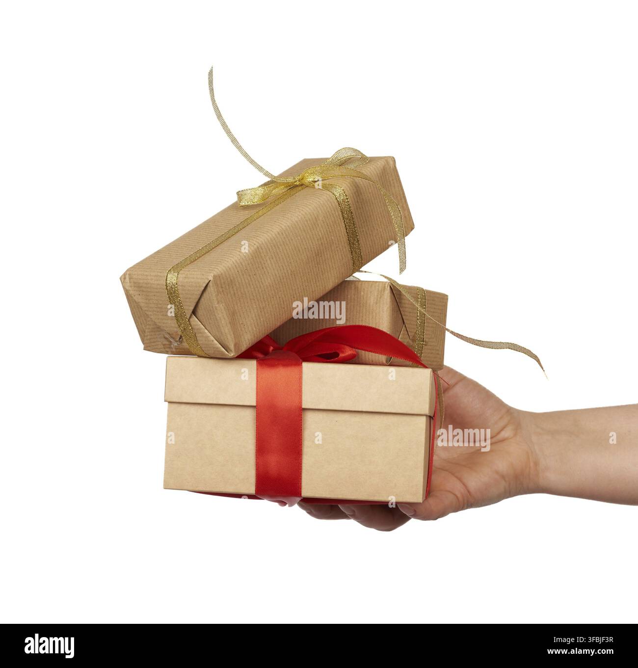 Hand holds a stack of wrapped gifts in brown craft paper with tied silk bows, subject is isolated on a white background Stock Photo