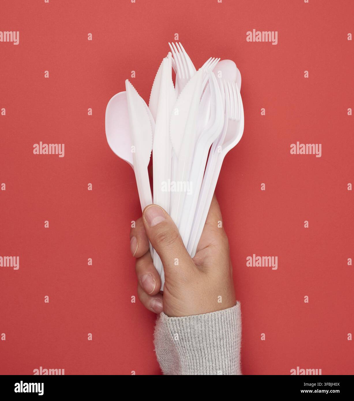 Stack of plastic forks and spoons on red background, close up Stock Photo