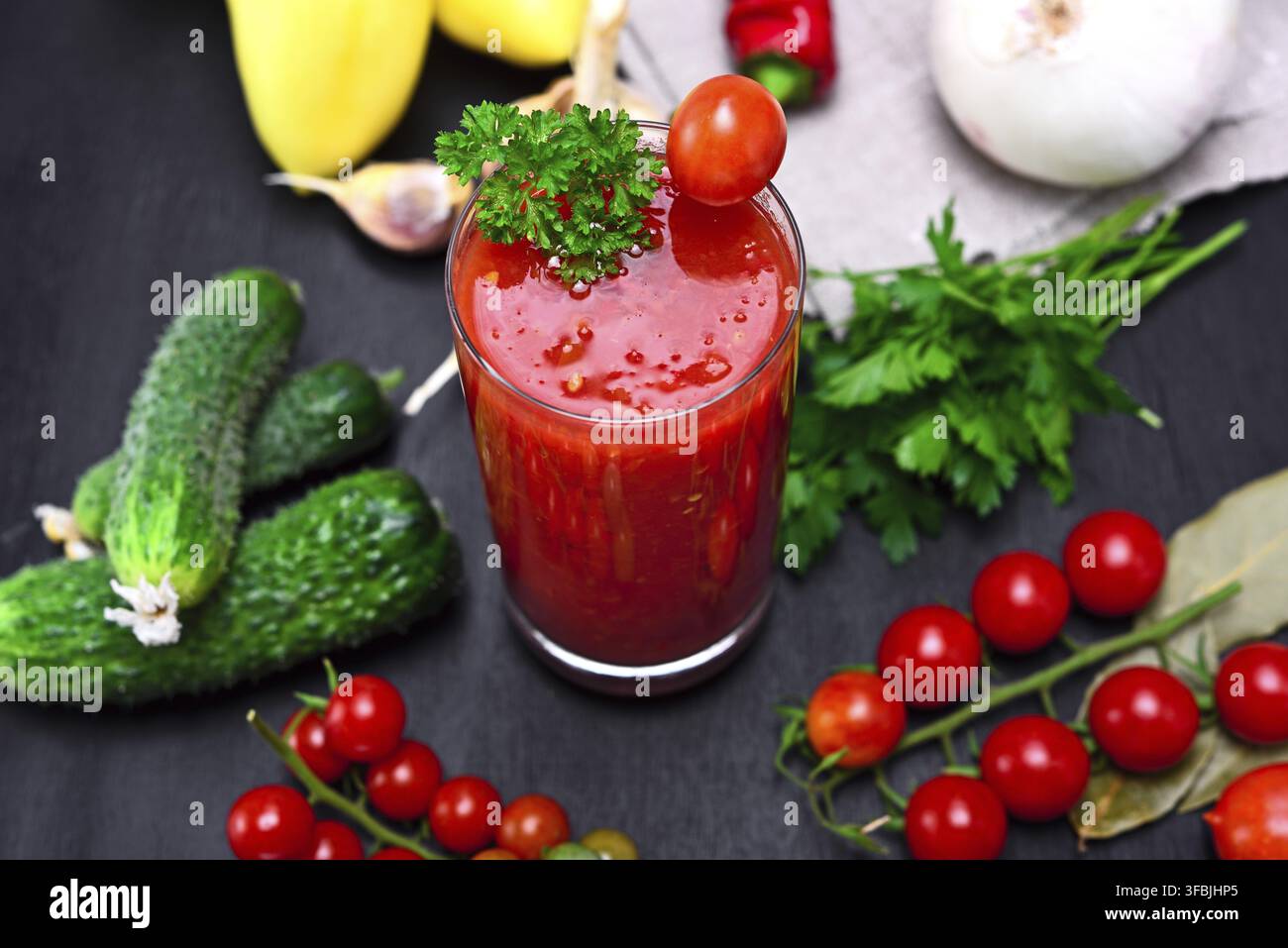 Glass of freshly squeezed tomato juice on a table with vegetables, top view Stock Photo