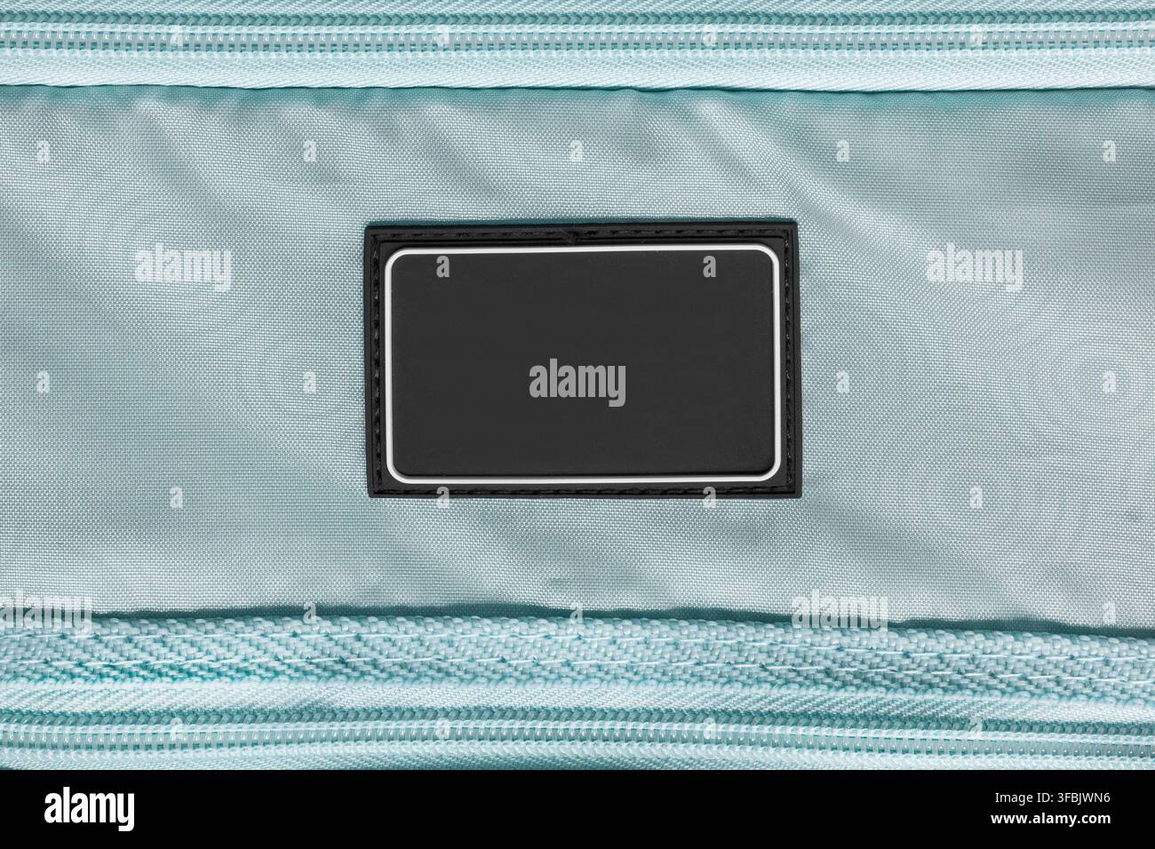 Black rubber blank patch stitched on light blue fabric background Stock Photo