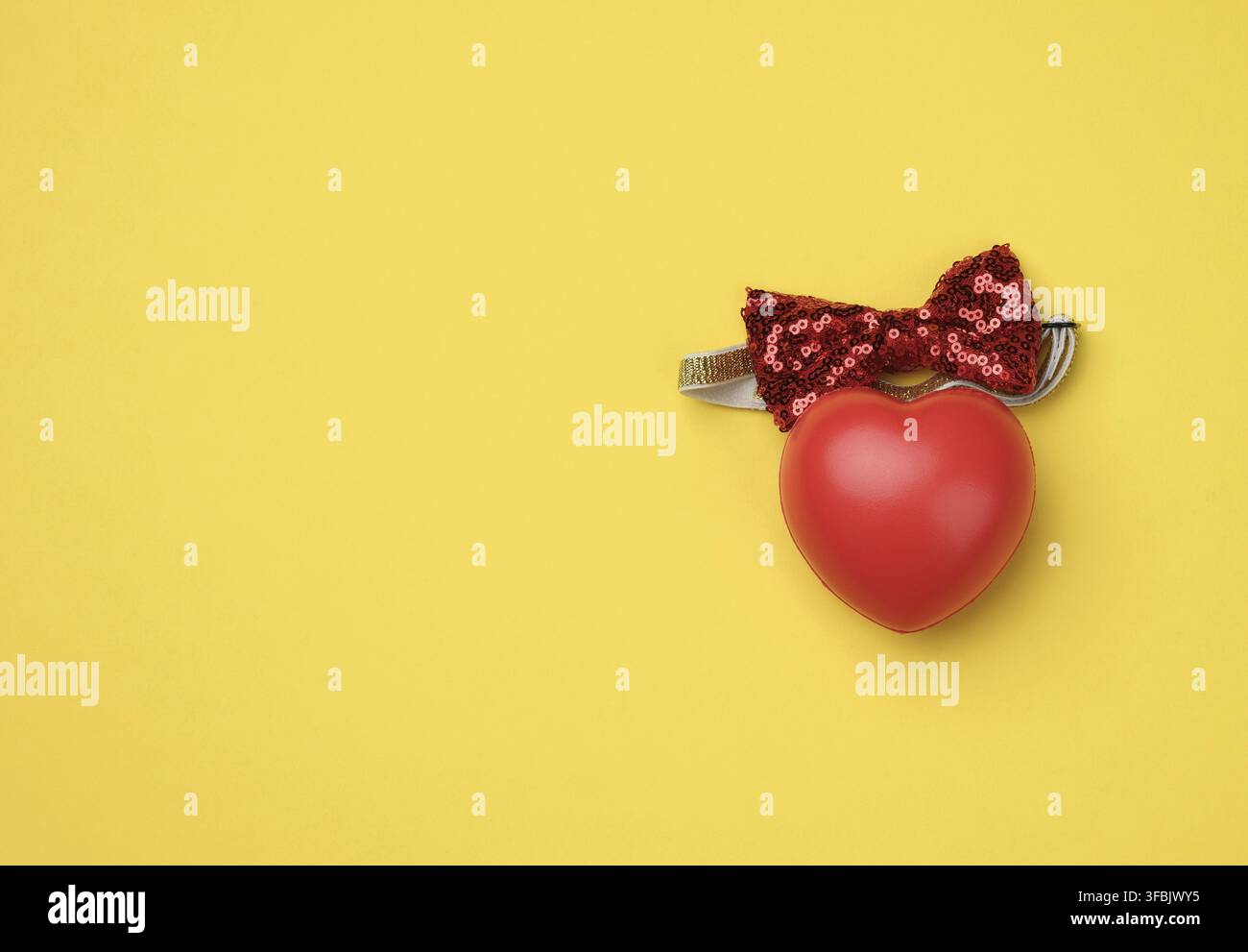 Red rubber heart on a yellow background, top view Stock Photo