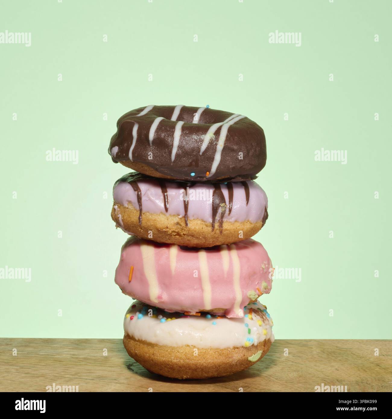 Stack of donuts with different toppings and glazes, green background Stock Photo