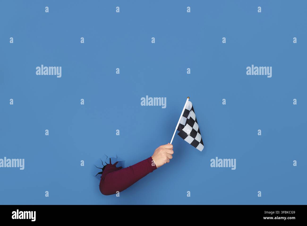 Hand holding checkered flag over blue background Stock Photo