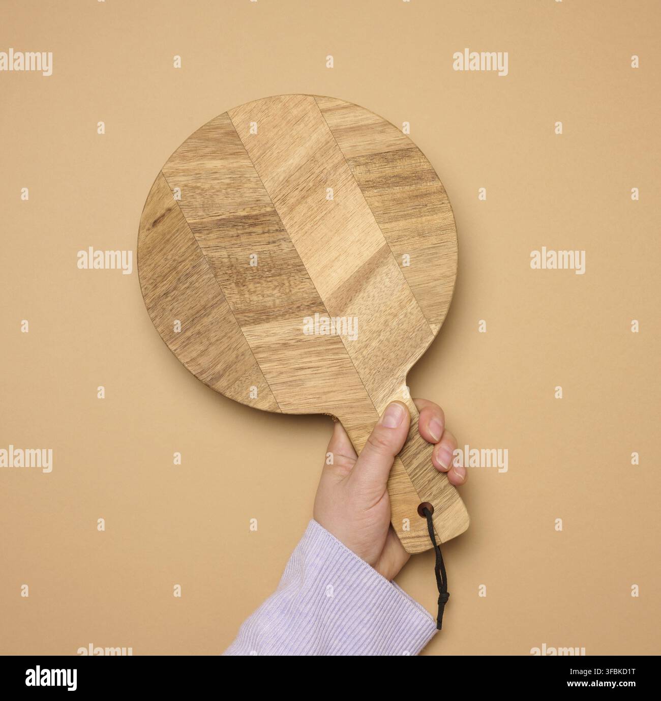 Woman's hand holding empty round wooden cutting board, top view Stock Photo