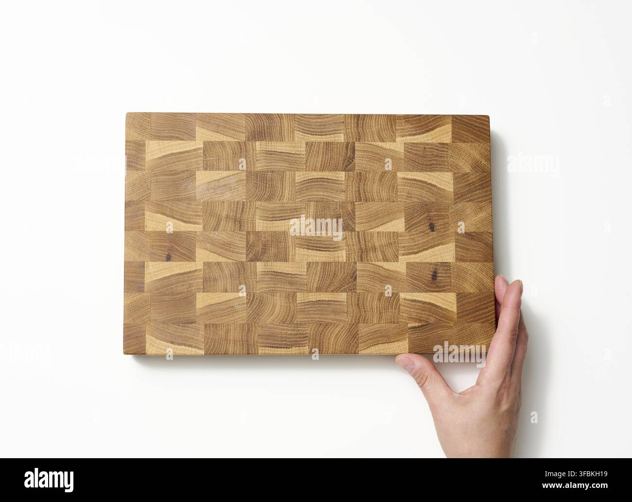 Female hands hold empty rectangular brown wooden chopping board on white background Stock Photo