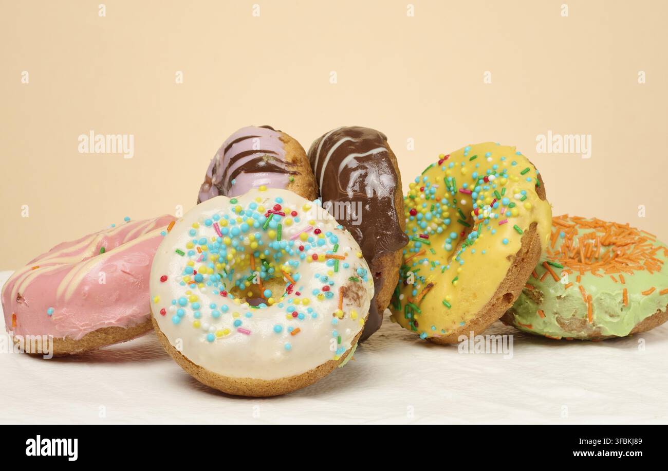 Stack of donuts with different toppings and glazes, beige background Stock Photo
