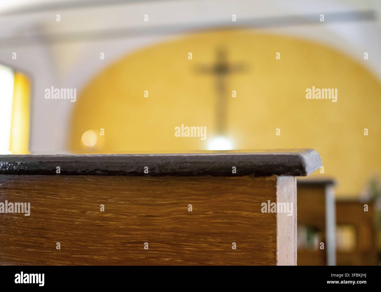 Image of Dark brown church pews with light yellow background of altar and crucifix Stock Photo