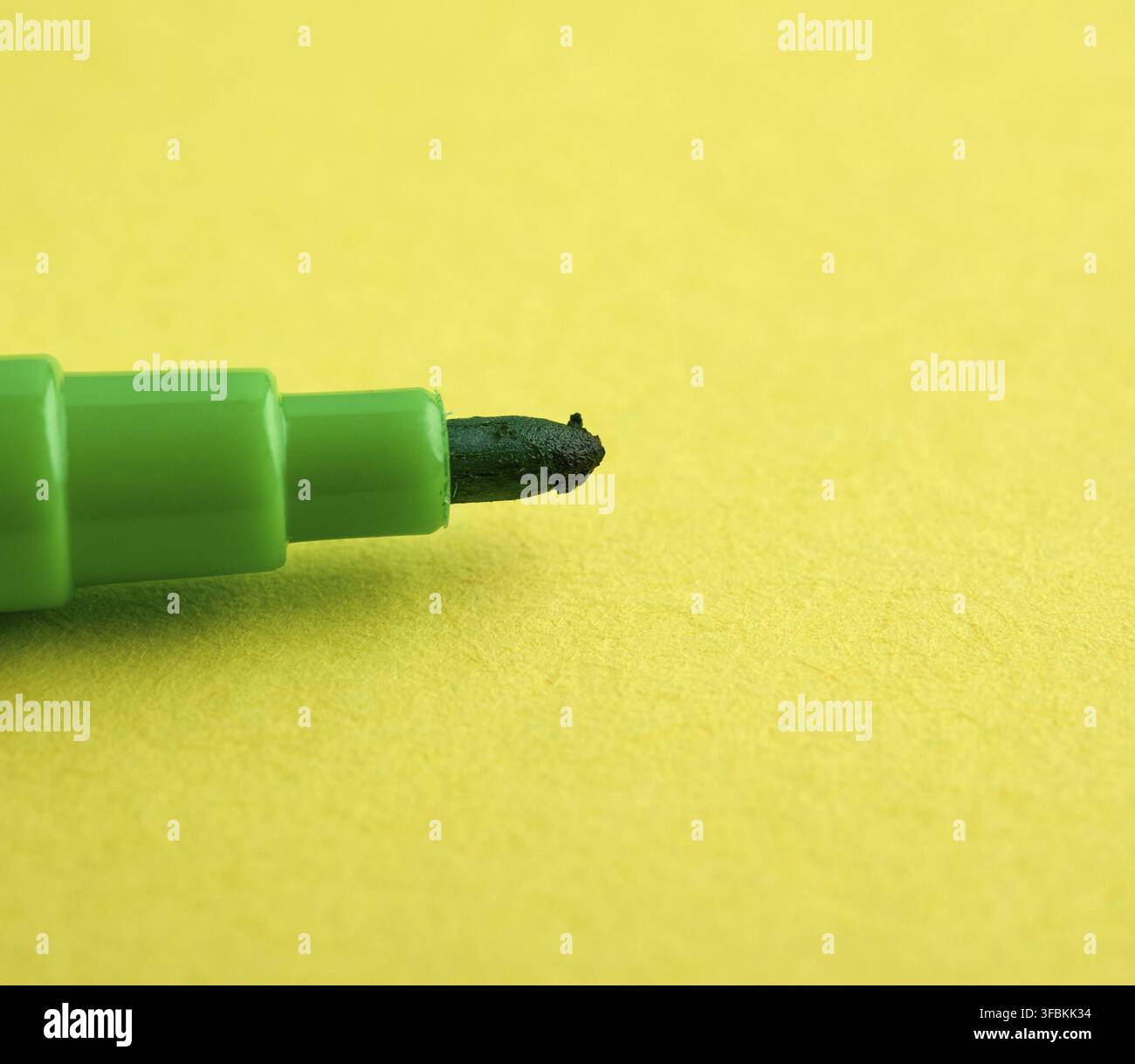 Green felt-tip pen on a yellow background, macro Stock Photo