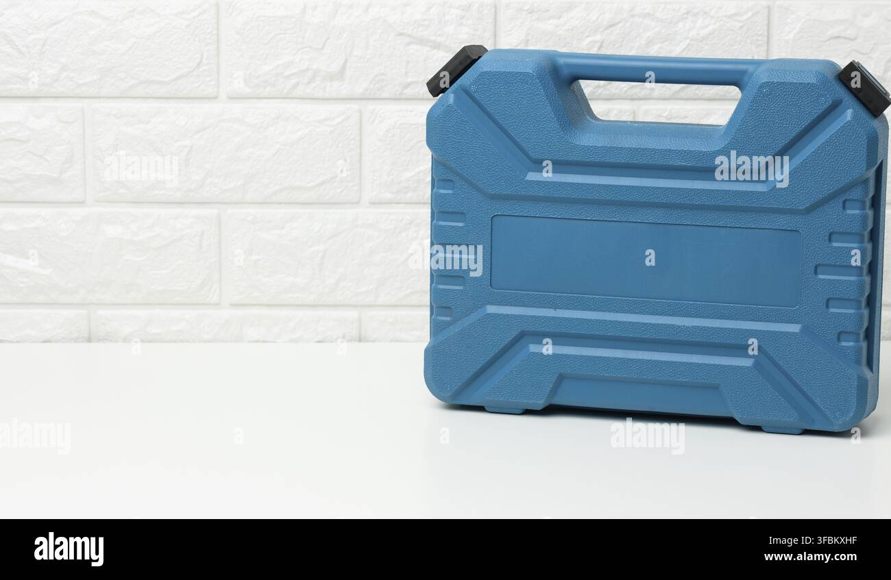 Closed blue plastic tool case stands on a white table Stock Photo