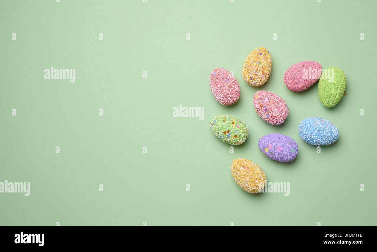 Multicolored decorative Easter eggs on green background, top view. Copy space Stock Photo